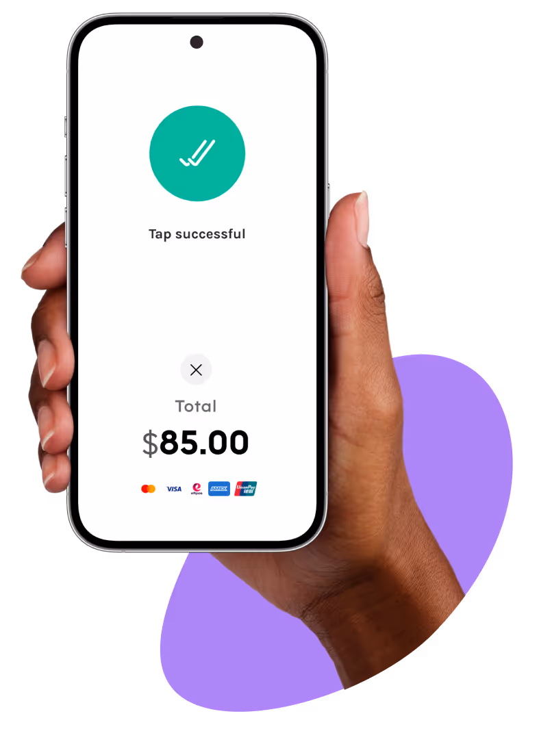 Hand holding a smartphone displaying a successful tap payment for $85.00 with multiple payment options, including Visa, Mastercard, and Amex.