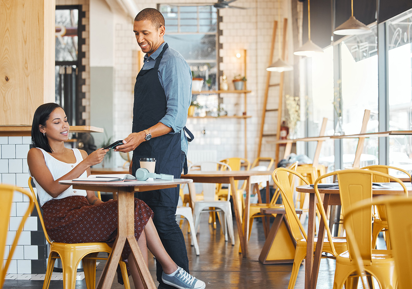 Customer using a mobile eftpos machine to pay via phone at a café, highlighting modern eftpos solutions and payment apps in Australia.