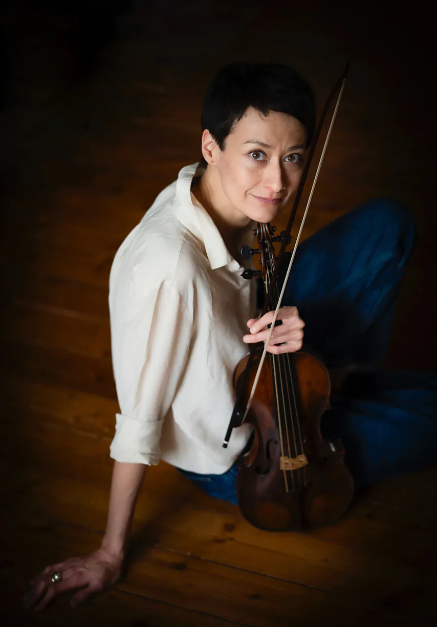 Joanna sitting on the floor holding a violin.