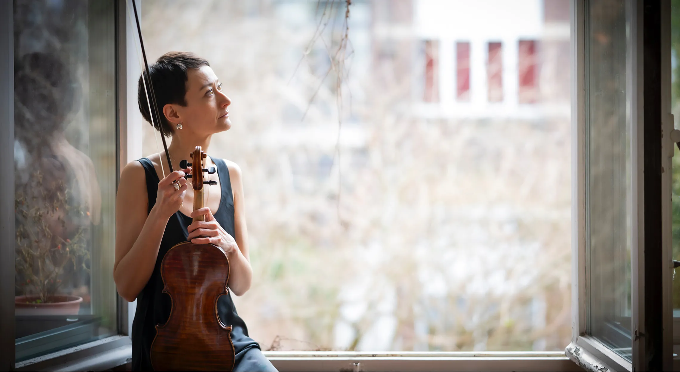 Joanna sitting on a window sill holding a violin.