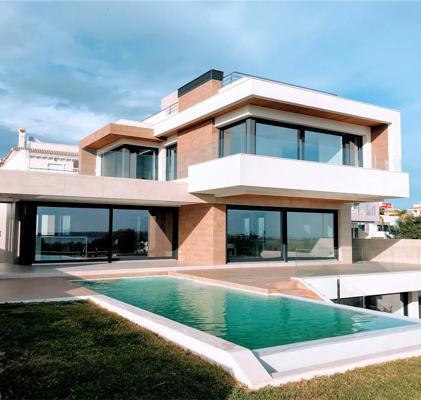 Modern two-story house with large windows and turquoise swimming pool