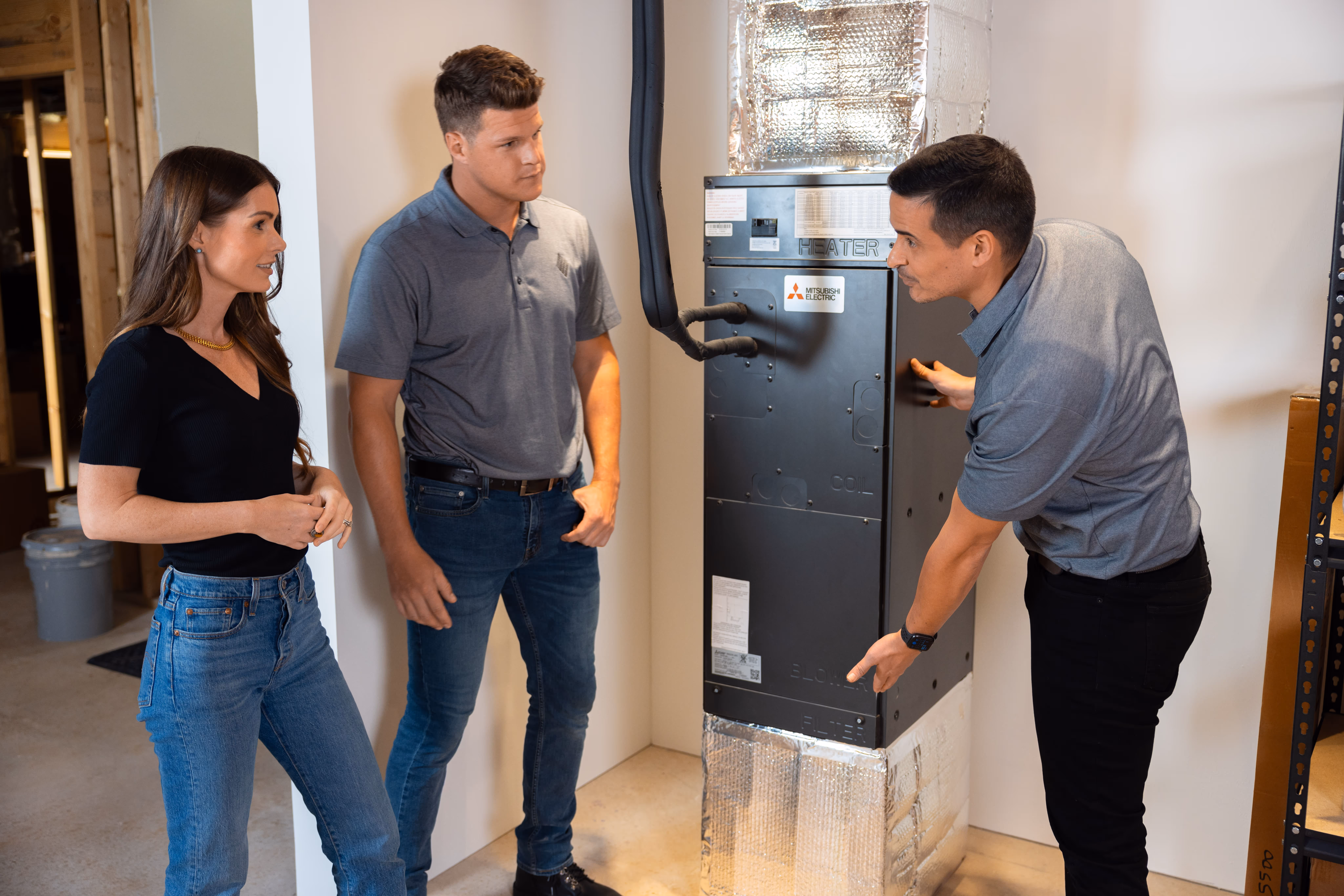 An HVAC technician explaining a new furnace to the homeowners.