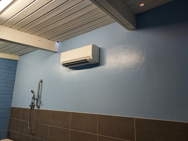Modern bathroom featuring a wall-mounted air conditioner and stylish blue accent walls.
