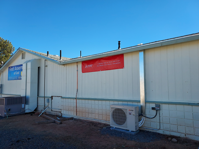 First Assembly of God building features an HVAC unit and a promotional banner for Mitsubishi Electric.
