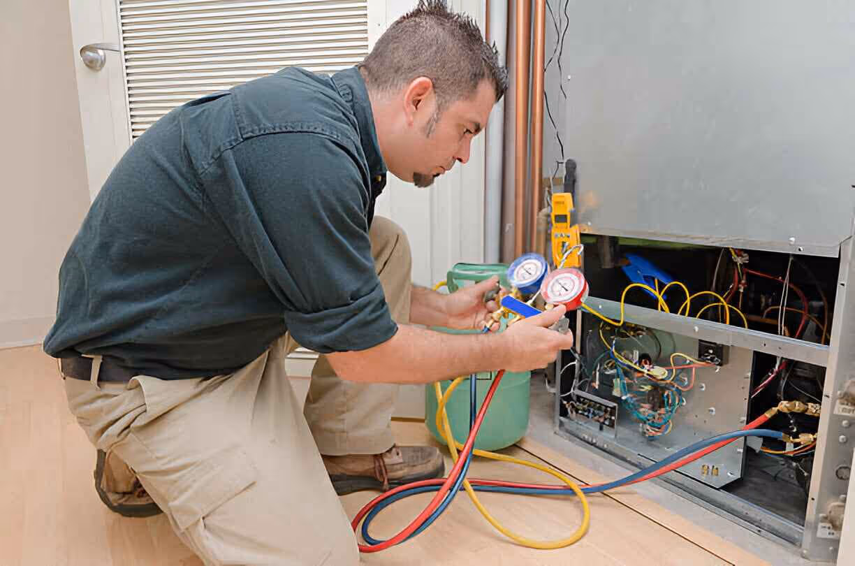 Technician checking pressure gauges on HVAC system electrical components
