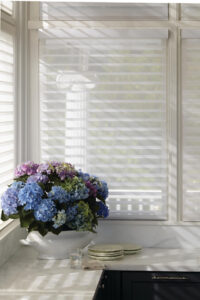 A bouquet of green and purple flowers sits on a counter next to a window