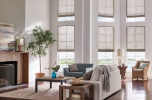 A living room with lots of windows that have beige roller shades