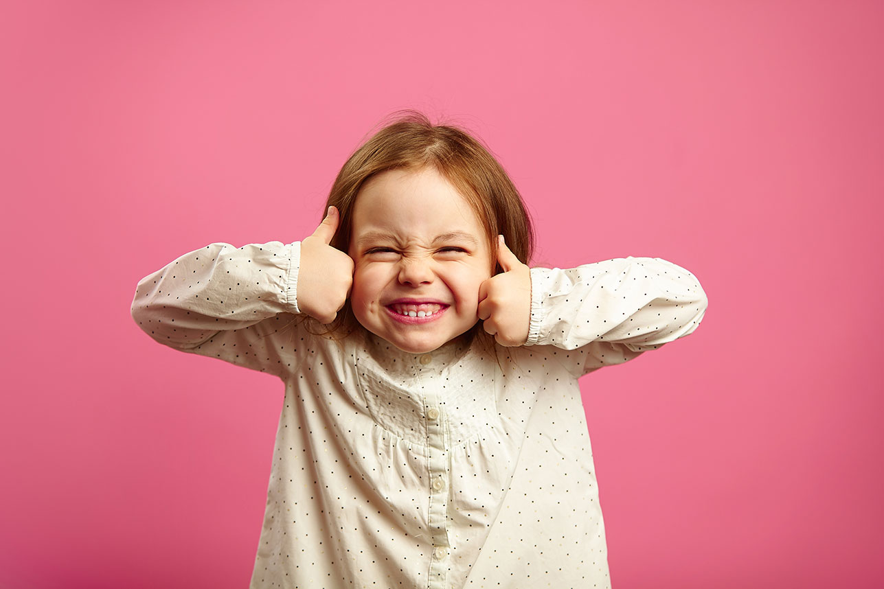 A smiling girl gives two enthusiastic thumbs. Represents positivity and treatment success.