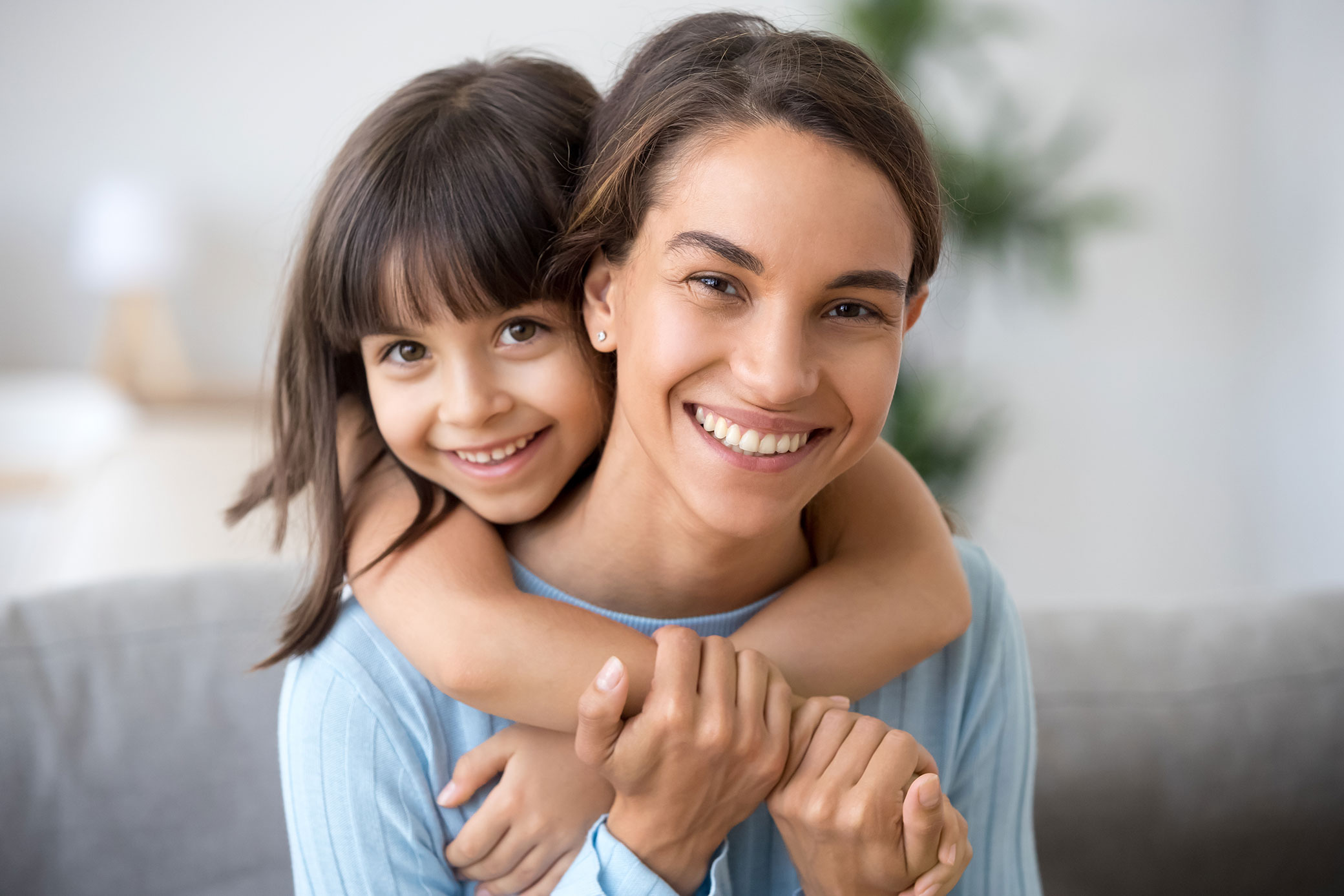 A young girl hugs her mother. Cozy indoor setting suggests relief, connection, and peace of mind after treatment.