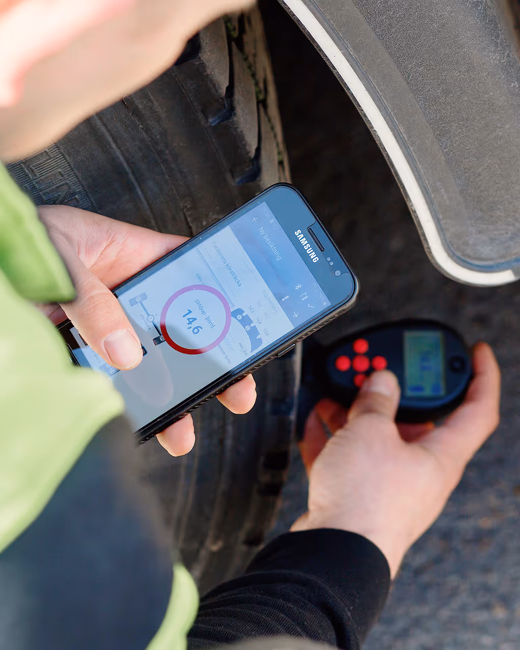 A close up of a person holding a phone and inspecting tires.