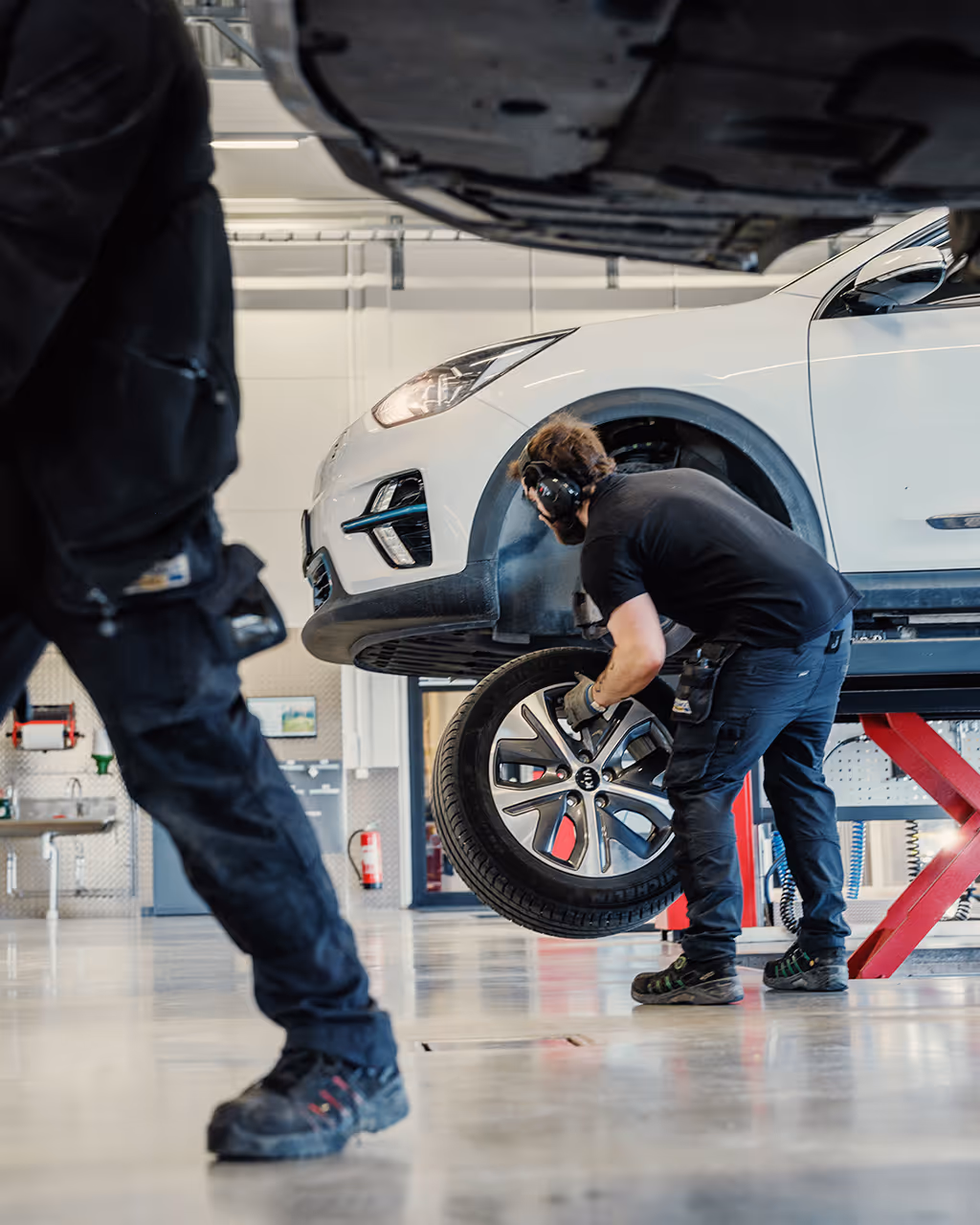 A bright service center where two workers are handling tires.