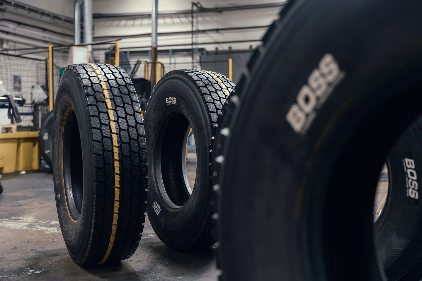 Several large truck tires standing upright in an industrial warehouse, some marked with the brand name BOSS.