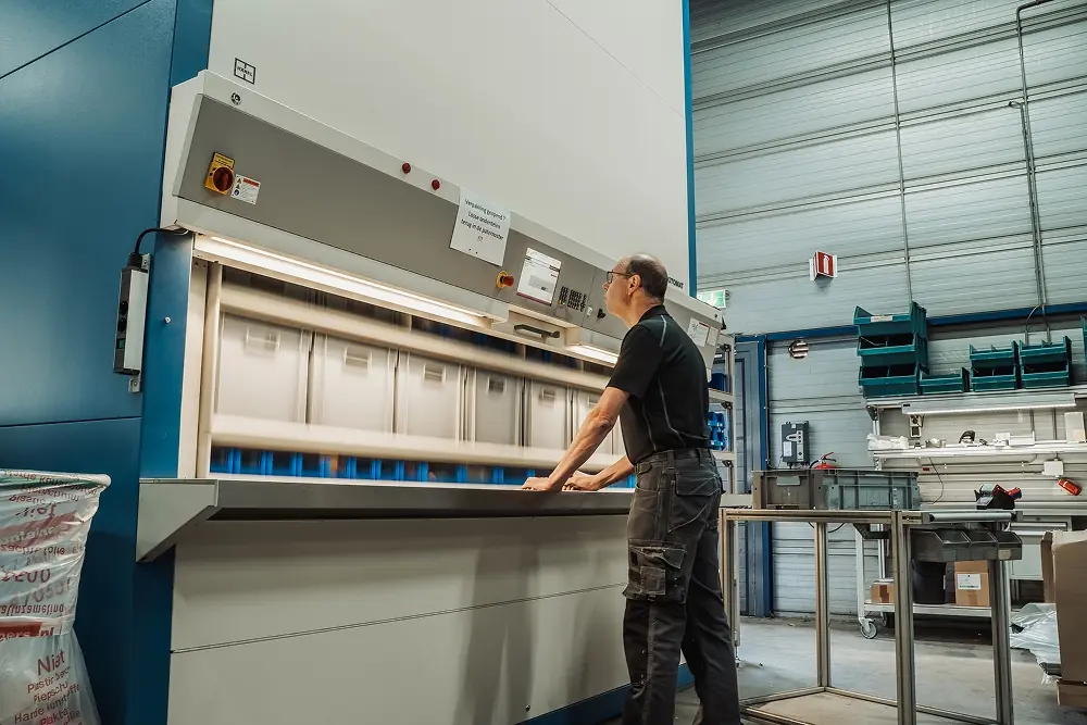 Man bedient een grote industriële machine in een magazijnomgeving.