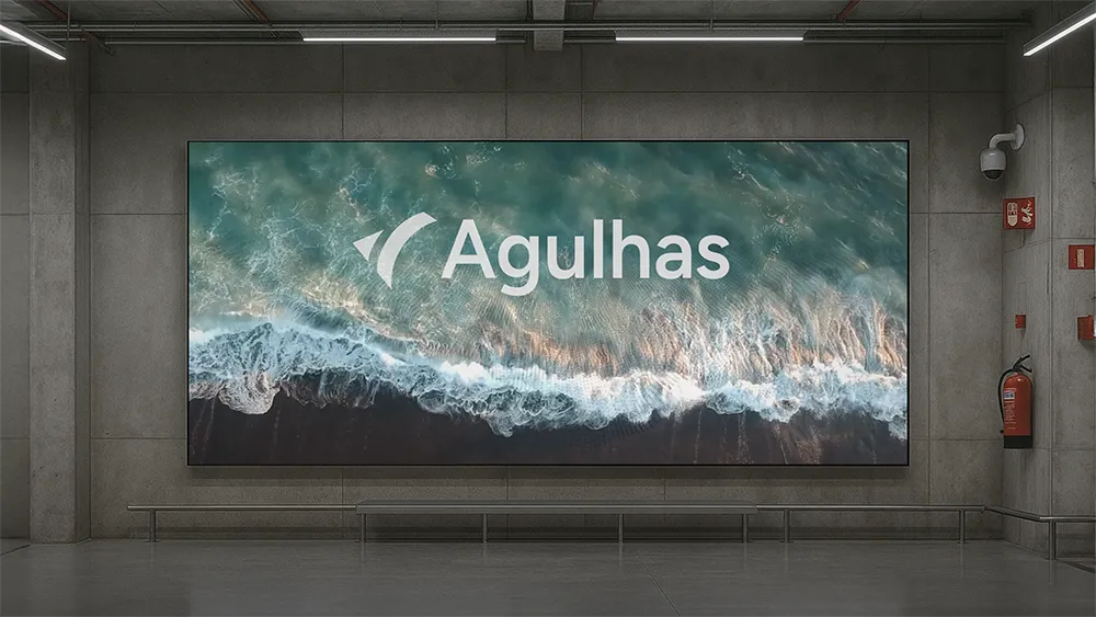 Digital display in a concrete room showing aerial view of ocean waves with the word Agulhas overlaid.