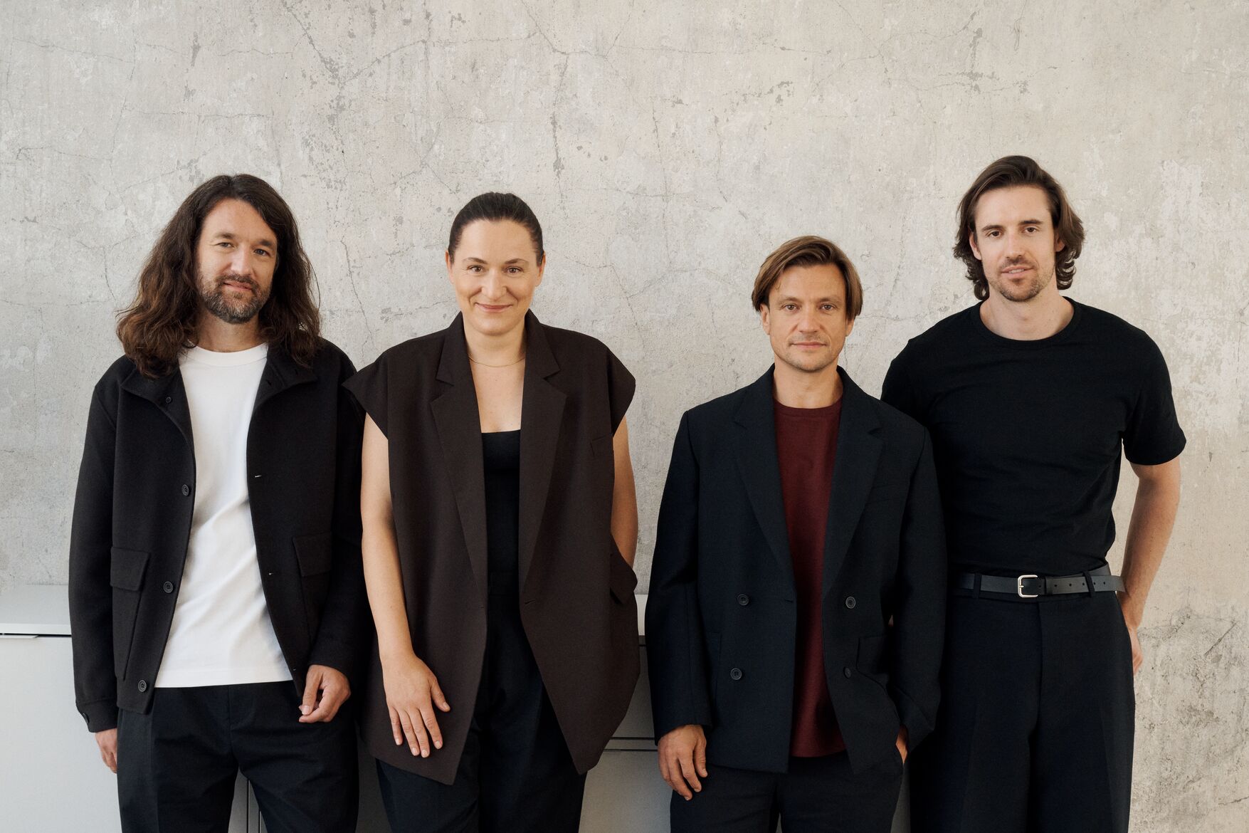 Four people dressed in black standing together in an editorial photo