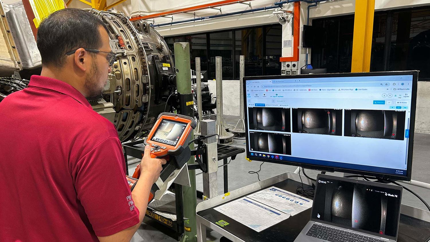 Man working with industrial inspection equipment and monitors in a factory setting