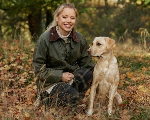 Person kneeling outdoors with a golden retriever dog