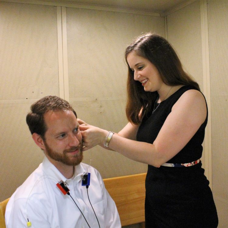 Dr Laura in a black sleeveless dress standing with hands on hips in front of two Auburn University diplomas on a wall.