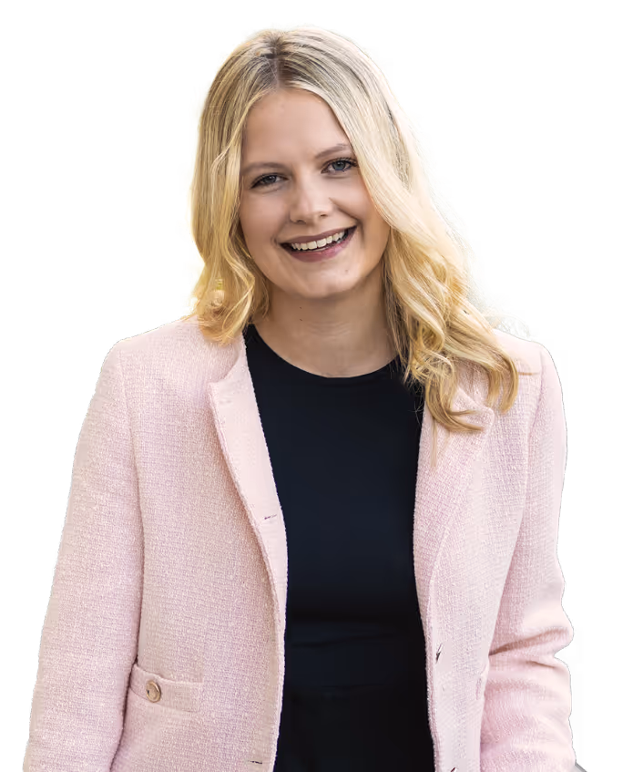 Smiling woman in a pink blazer with long blonde hair.