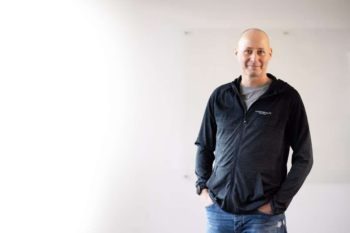 Employee of Theobald Software GmbH in a black jacket in front of a white wall.