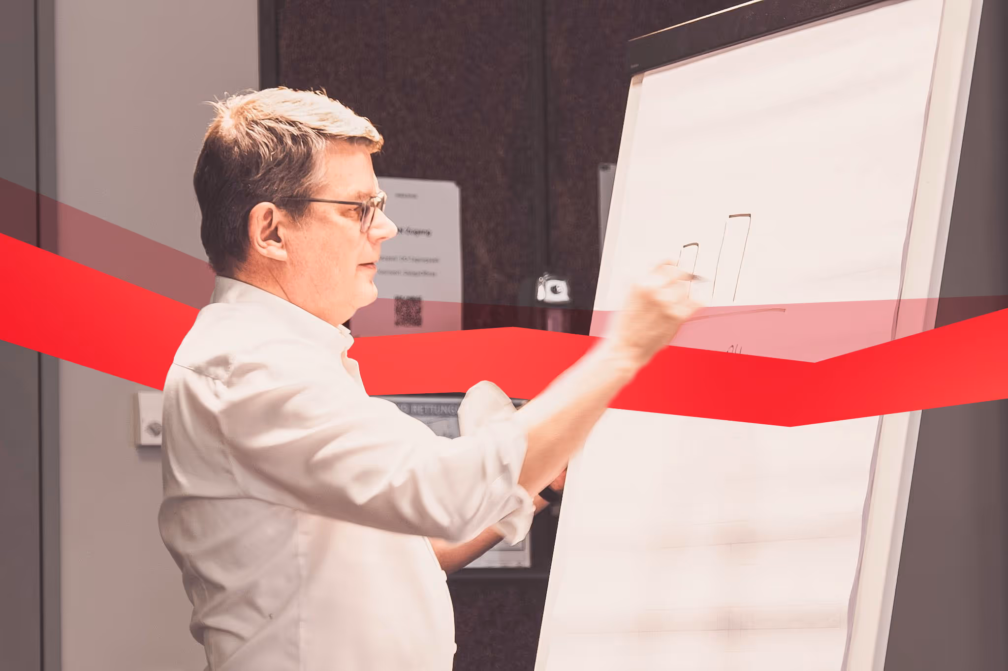 Theobald Software employee in a white shirt shows something on a whiteboard and a string of red data leads through the image.