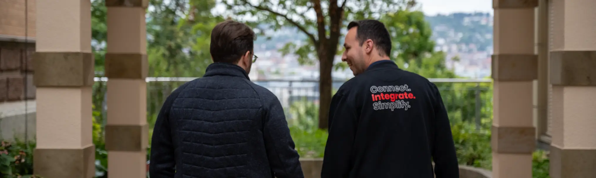 Zwei Männer in dunklen Jacken von hinten.