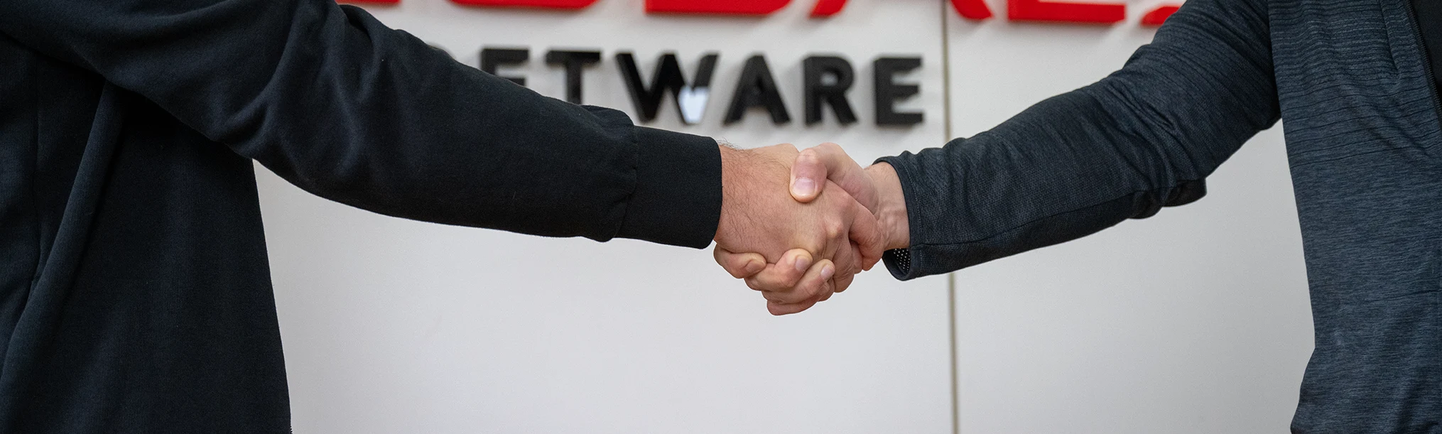 Zwei Menschen in dunkler Kleidung geben sich die Hände.