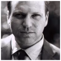 Black-and-white portrait of Gary Andrew Poole wearing a suit and tie, looking directly at the camera with a neutral expression. 