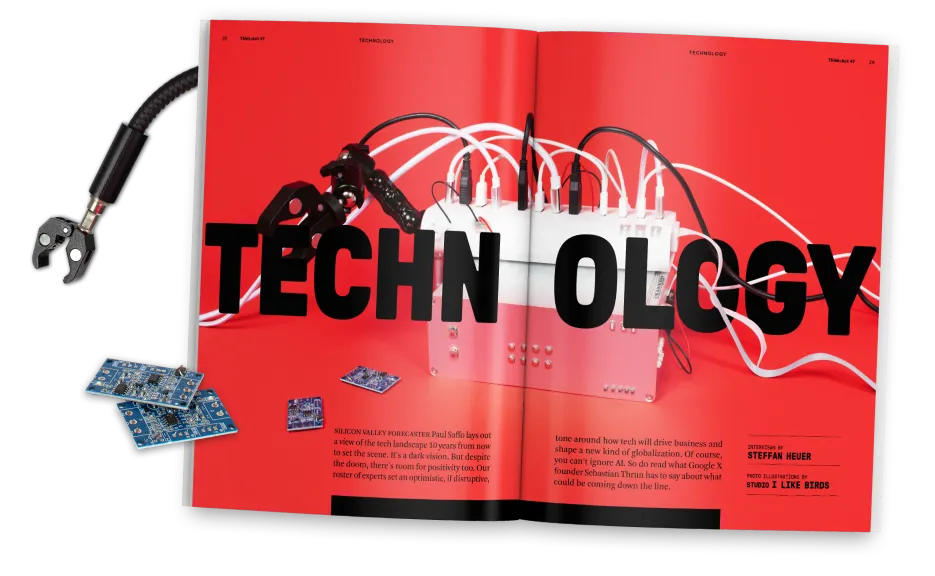 Open magazine spread with a red background showing a robotic clamp arm, tangled white and black cables and various electronic components. The large black headline across both pages reads “TECHNOLOGY.” Additional circuit boards and a robotic claw are placed beside the magazine.