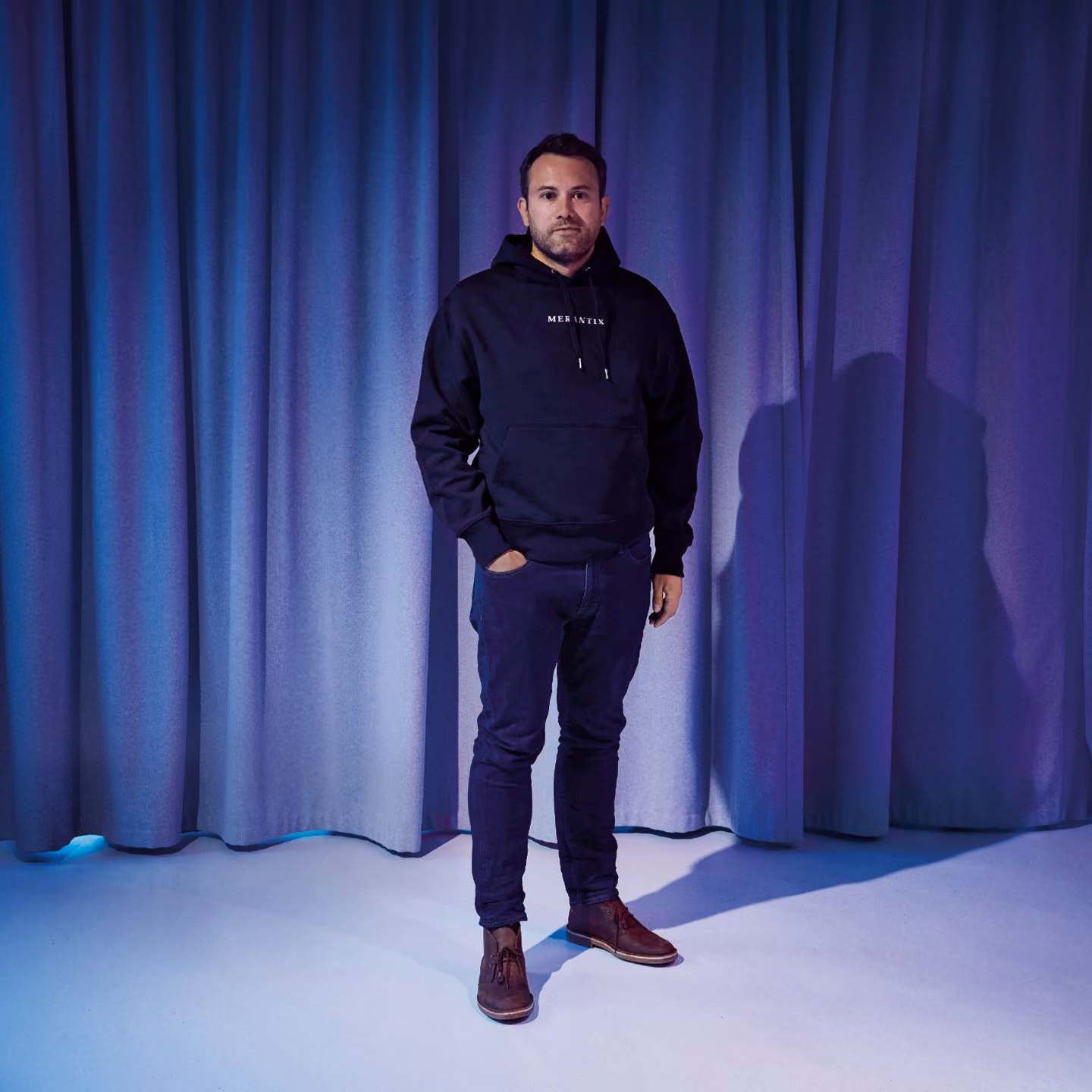 KI-generiertes Porträt von Rasmus Rothe, Gründer von Merantix Capital, in einem Merantix-Hoodie vor einem blau beleuchteten Vorhang.