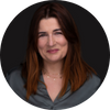 Portrait of a woman with long brown hair wearing a dark blouse, smiling slightly against a dark background.
