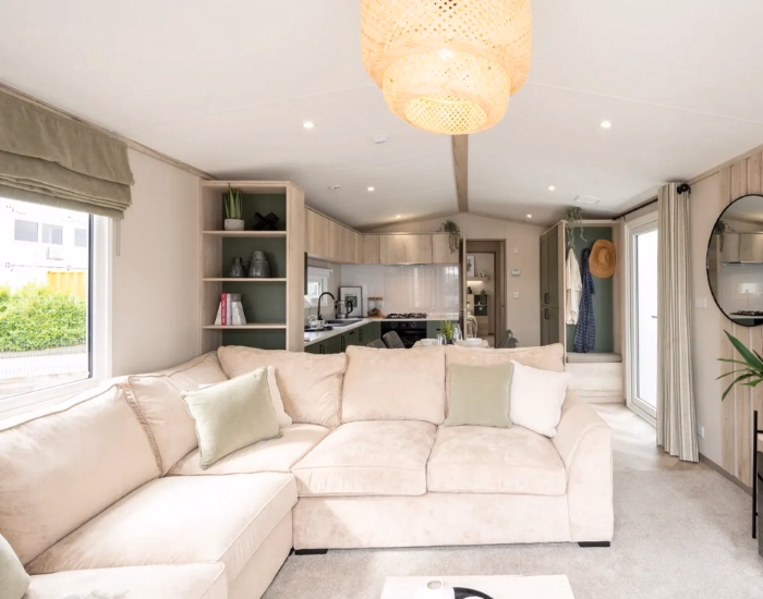 Ripley – Lichte woonkamer met beige hoekbank, open keuken en ramen rondom.
