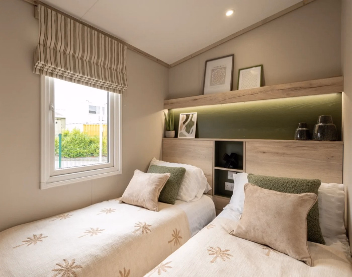 Ripley – Slaapkamer met twee eenpersoonsbedden, groene wandplank en raam.