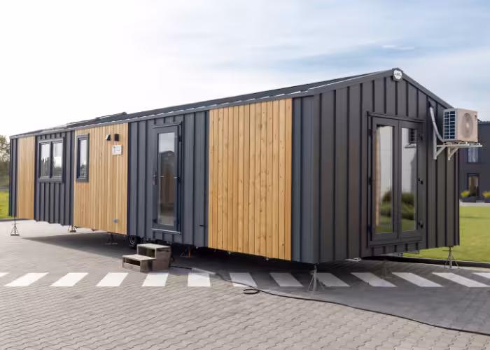 G-Spot – woonunit met zwarte en houten gevelpanelen, ramen, deuren en airconditioning buiten.