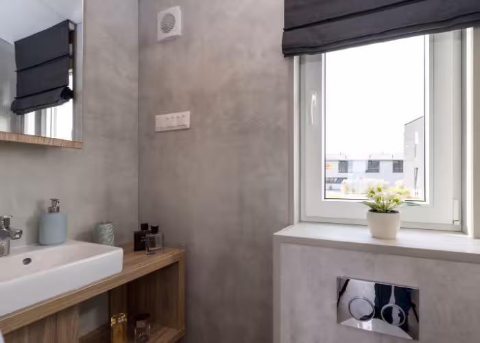 G-Spot – Moderne badkamer met wastafel, houten kast, bloem in pot en raam met zwart gordijn.
