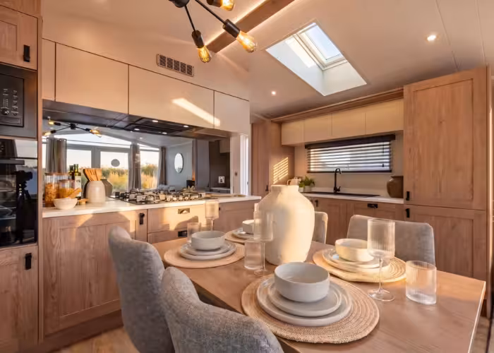 Lakewood – Gezellige kleine keuken en eetkamer met houtafwerking, tafel met gedekte borden en een grote vaas.