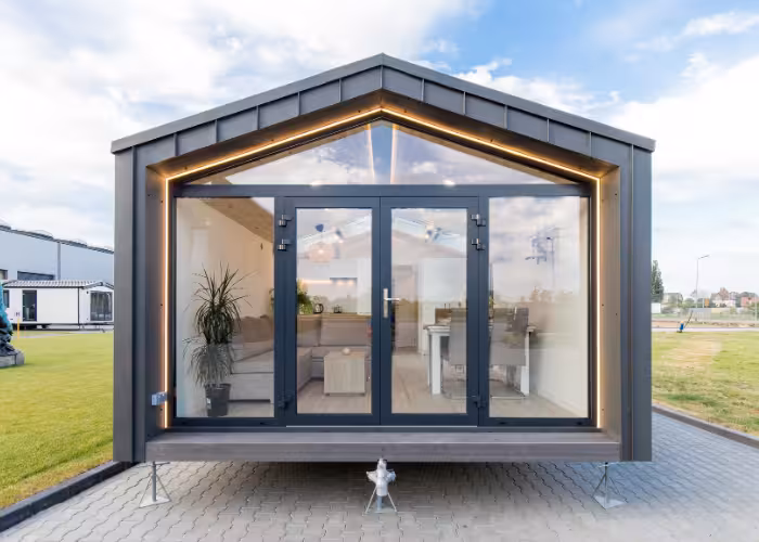Capri – Moderne zwarte woonunit met glazen vouwwand en houten interieur op een verharde ondergrond.