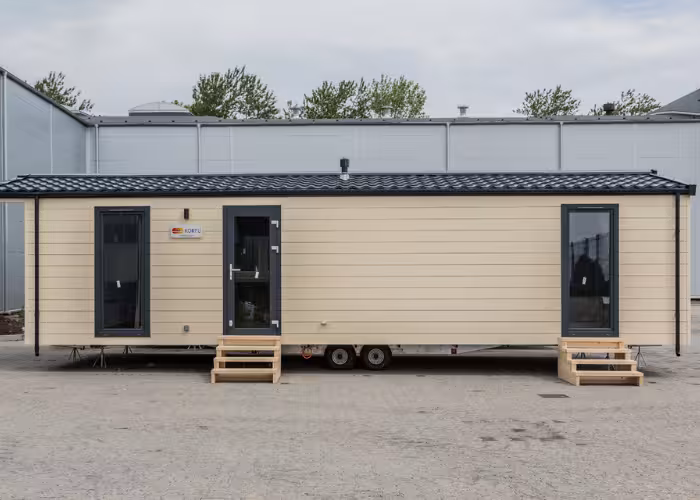 Korfu – Beige woonunit met twee ingangen en kleine houten trappen buiten, geparkeerd op beton.
