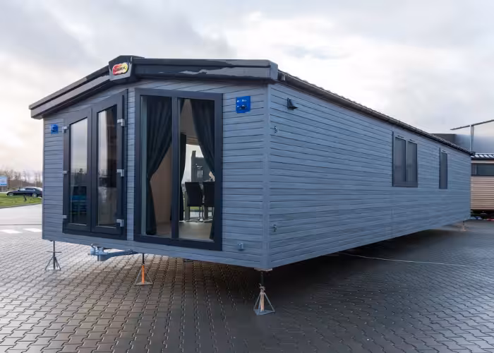 Murano – Grijze moderne woonunit met grote ramen en open deur op een betegeld oppervlak buiten.