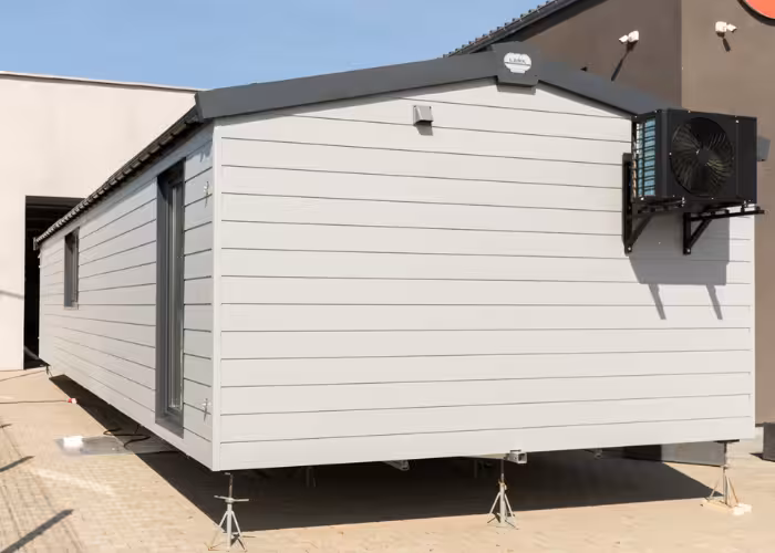 Chios – Moderne witte woonunit op steunpoten met airconditioning aan buitenmuur.