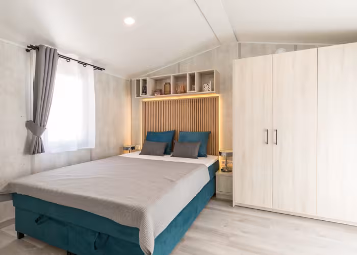 Chios – Slaapkamer met tweepersoonsbed, houten kast, grijze gordijnen en moderne inrichting.