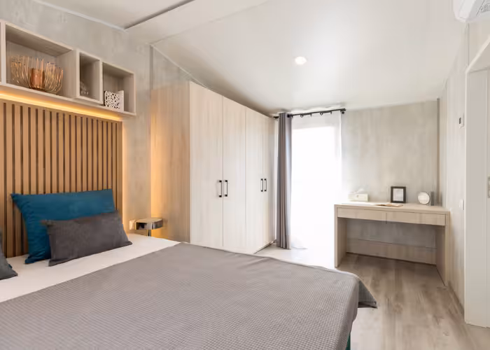 Chios – Slaapkamer met tweepersoonsbed, houten kledingkast, bureau en lichtgrijze decoratie.