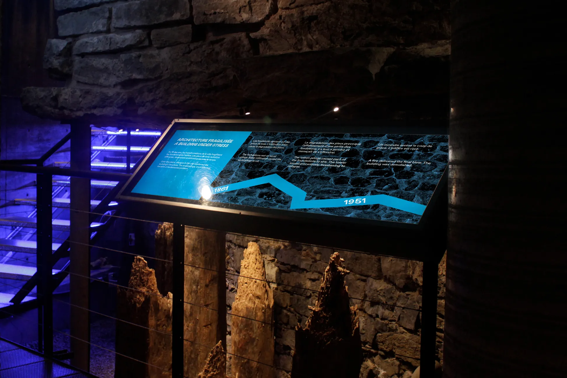 long blue history sign next to wooden pillars and bricks in dim room