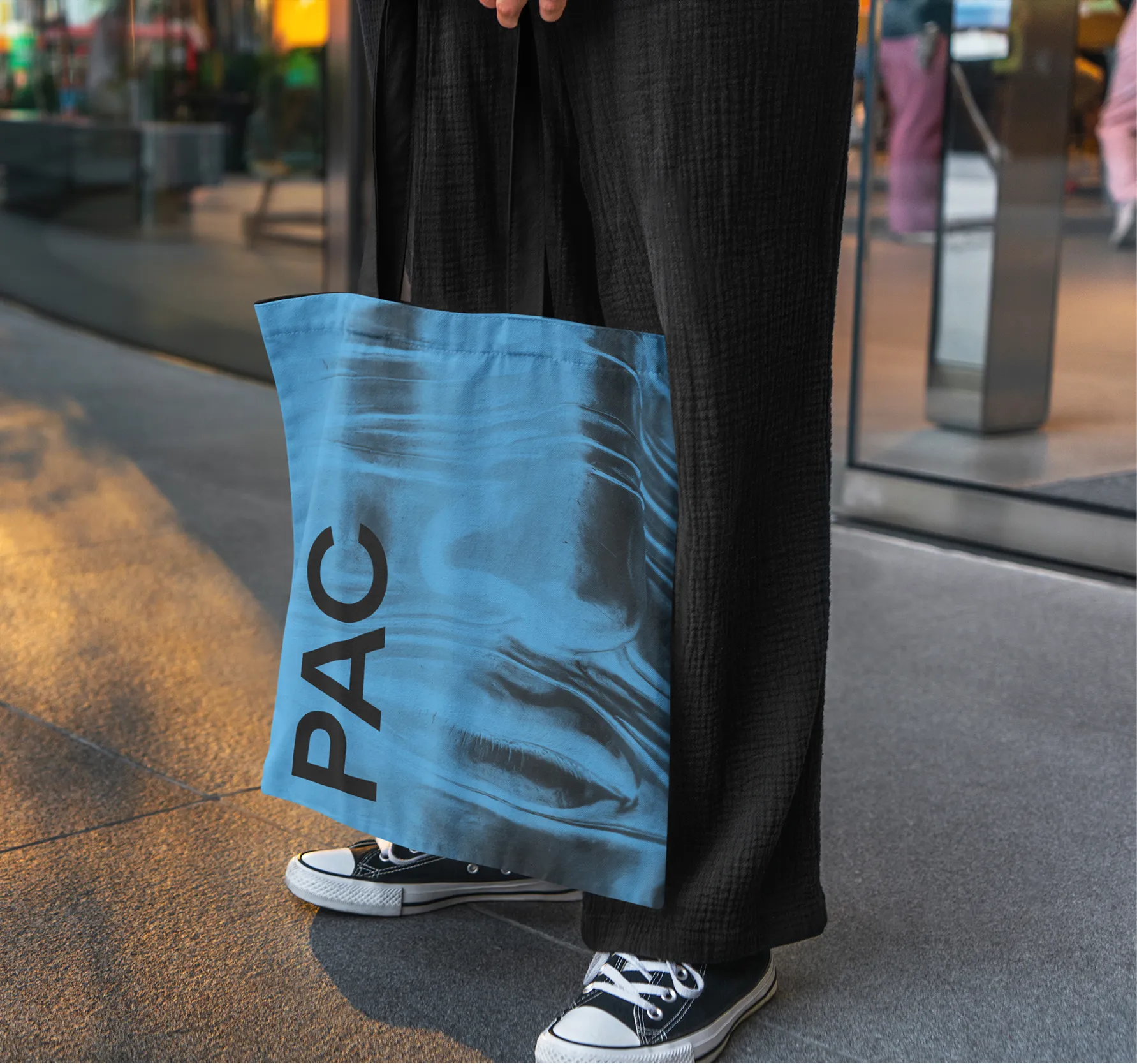 person standing in vans holding a tote bag designed in black pants