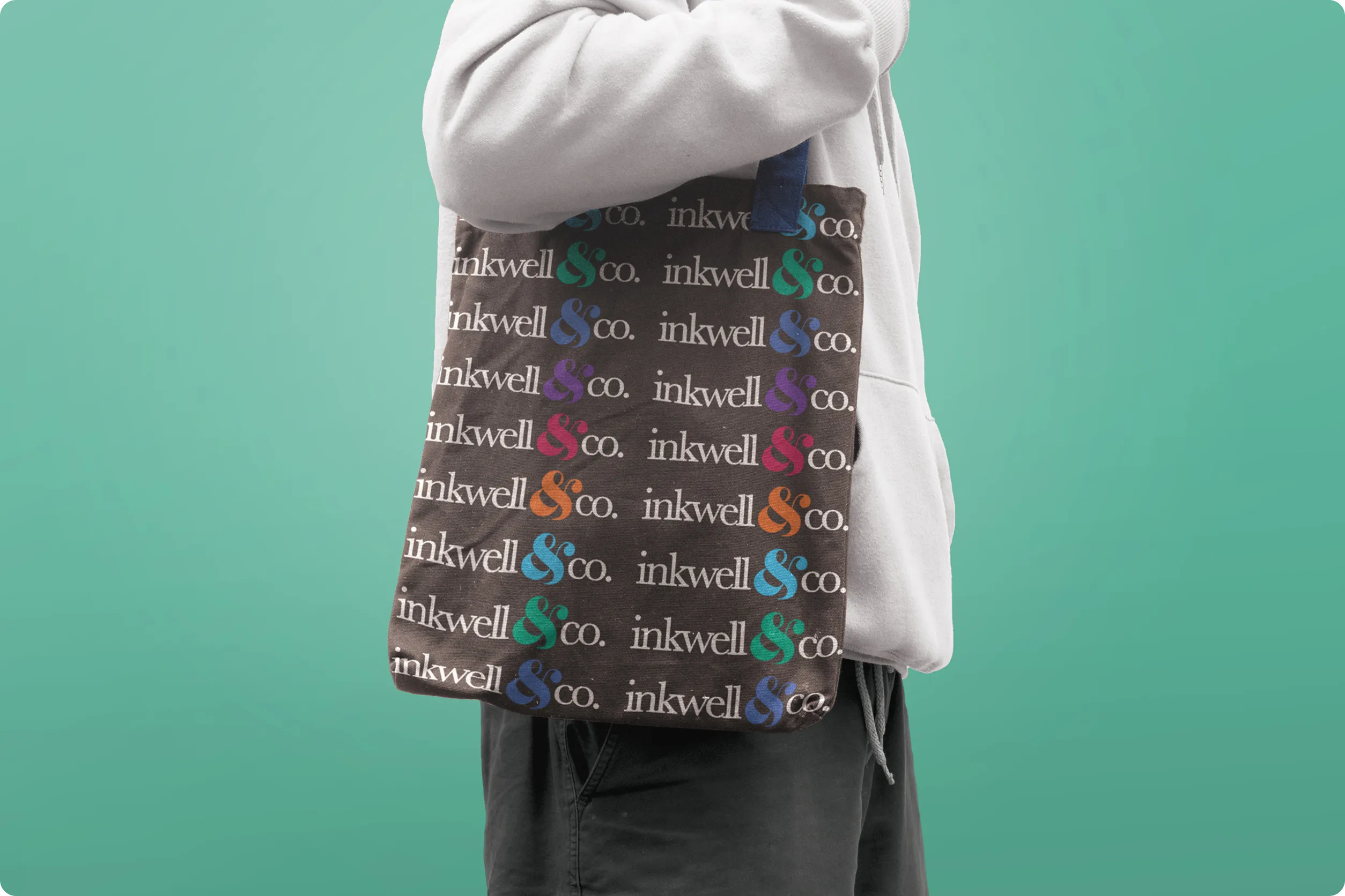 model with a dark gray branded tote bag on a green background