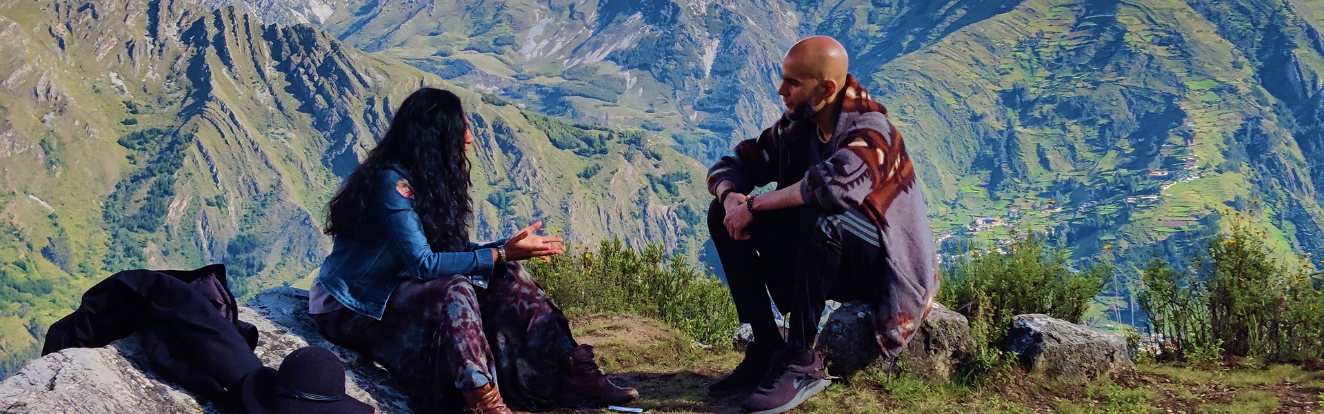 Smiling woman sitting in front of large tree roots surrounded by green foliage in a forest.