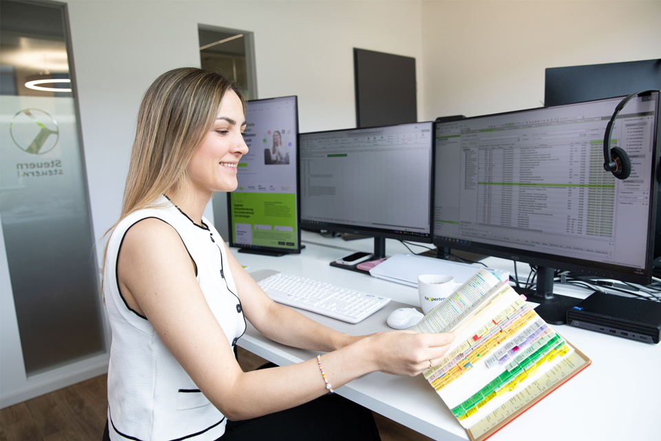 Steuerberaterin recherchiert steuerrechtliche Grundlagen im Gesetzbuch am Arbeitsplatz. 
