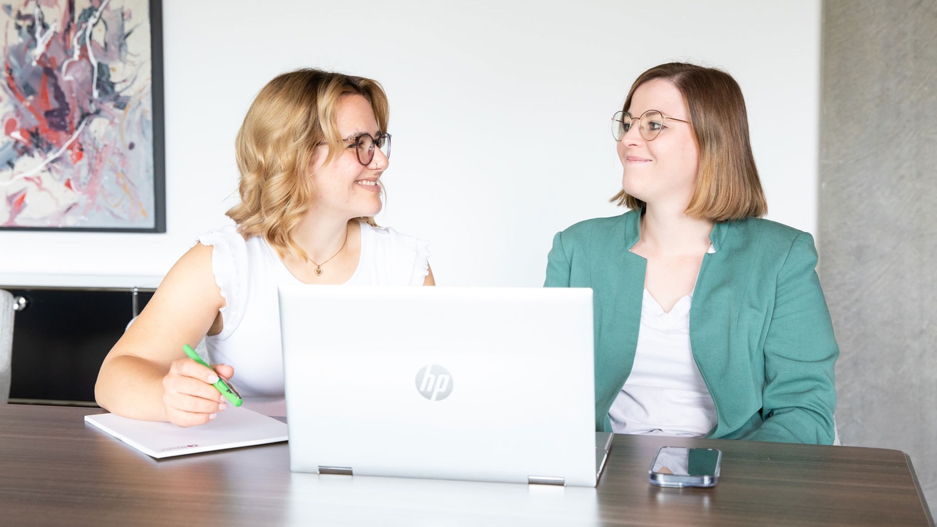 Austausch zwischen Mitarbeiterinnen mit Fokus auf Zusammenarbeit.