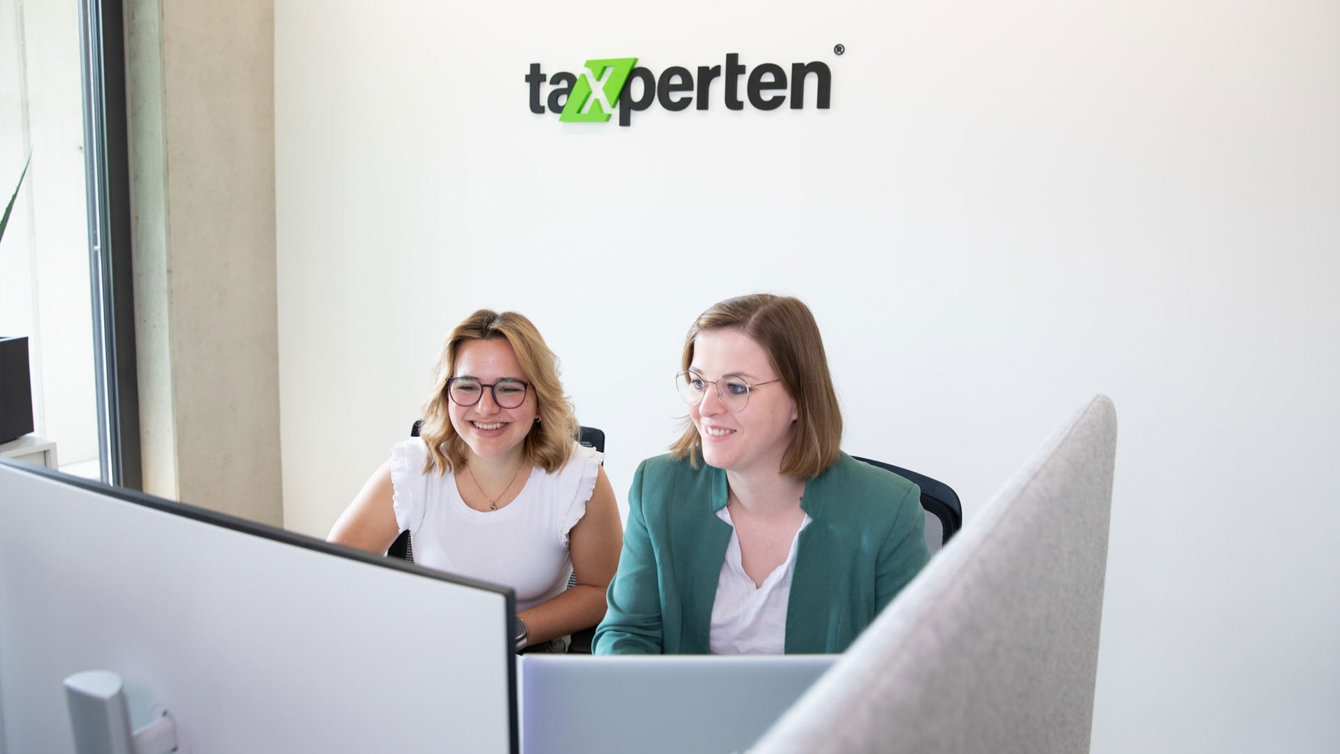 Berufliche Weiterbildung im Steuerwesen: Teamarbeit am Computer bei Taxperten.