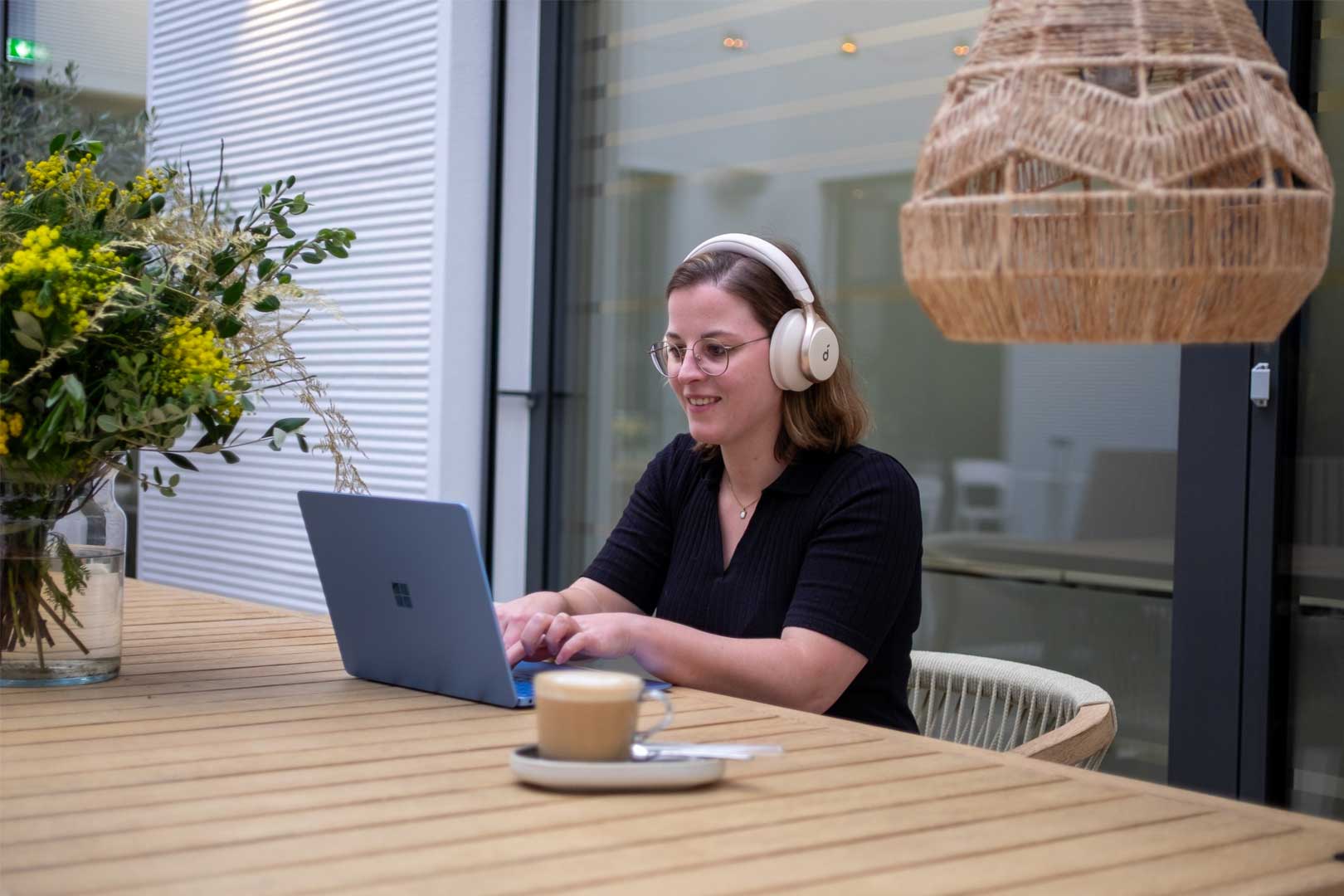 Mitarbeiterin arbeitet mit Laptop und Kopfhörern im Innenhof – ortsunabhängiges Arbeiten in der Steuerberatung